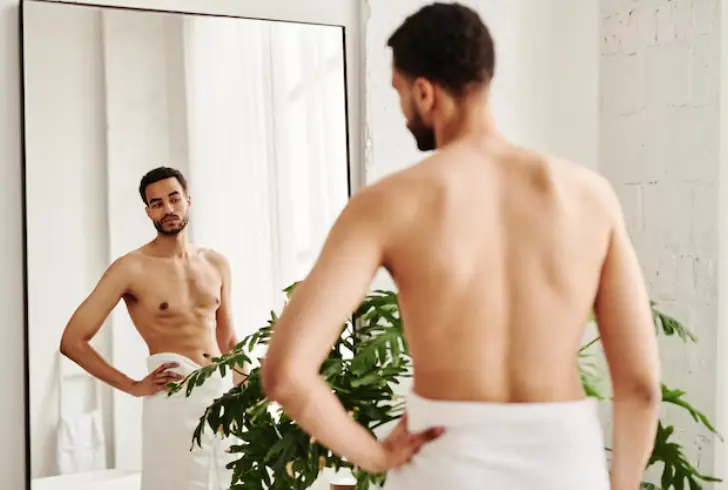 Person examining arm muscles in mirror